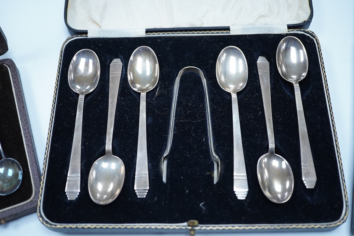 A cased set of six George VI Art Deco silver teaspoons and pair of sugar tongs, by C.W. Fletcher & Son Ltd, Sheffield, 1936, together with a cased set of six silver bean end coffee spoons and a cased set of six plated te